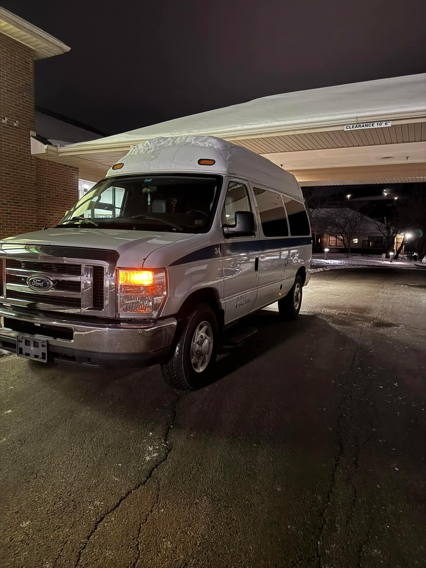 ATS wheelchair van under a facility entrance before dawn, with snow on the roof
